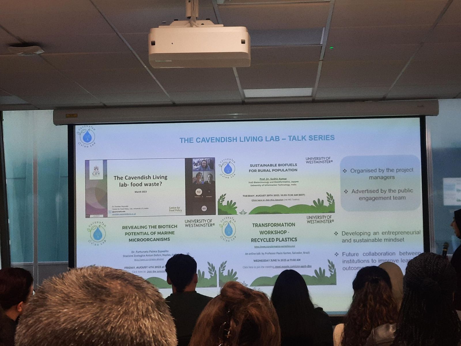 Projected slide titled The Cavendish Living Lab Talk Series, listing talks on food waste, sustainable biofuels, marine microorganisms and recycled plastics