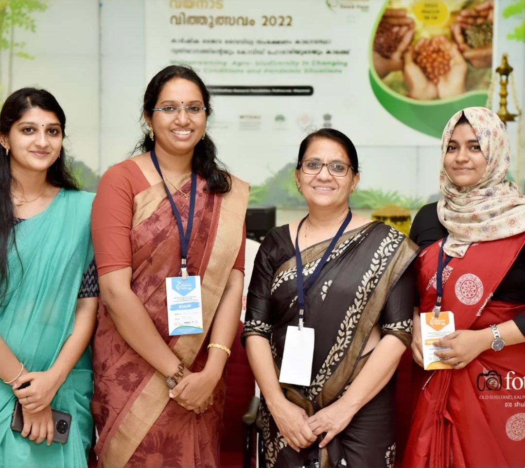 Four women with conference lanyards standing in front of a seed festival banner