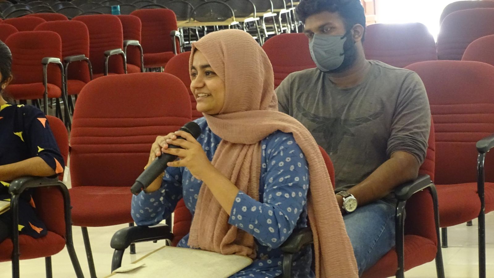 Subaiba speaking into a microphone from her seat in a lecture hall