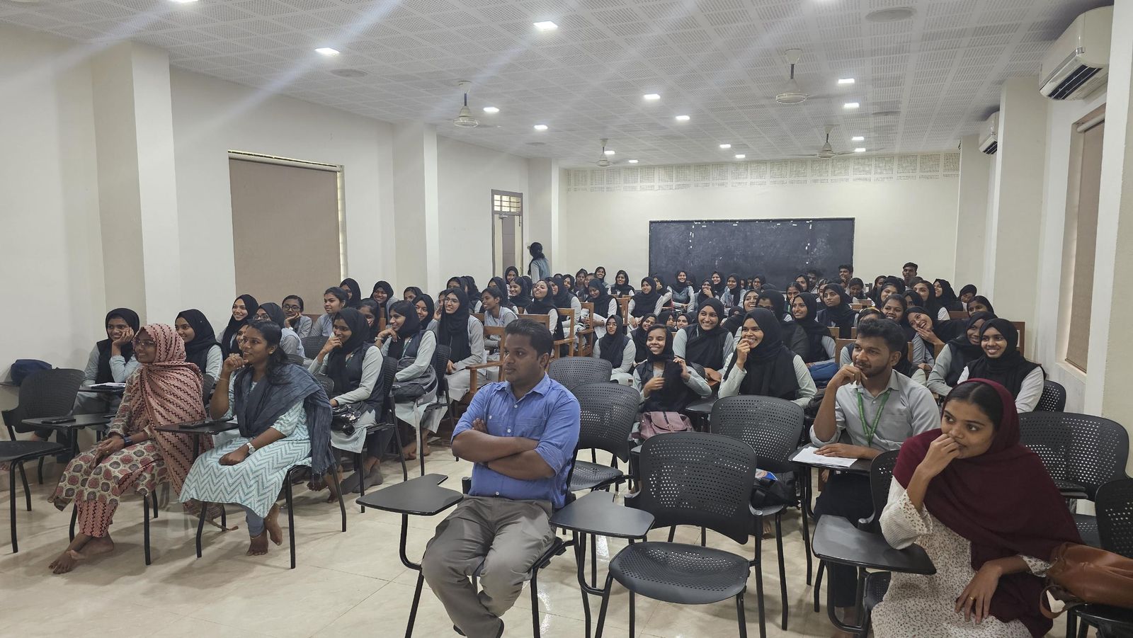 A seminar hall full of smiling students facing the speaker